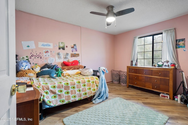 bedroom featuring ceiling fan, light hardwood / wood-style flooring, and a textured ceiling