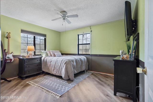 bedroom with multiple windows, ceiling fan, hardwood / wood-style floors, and a textured ceiling