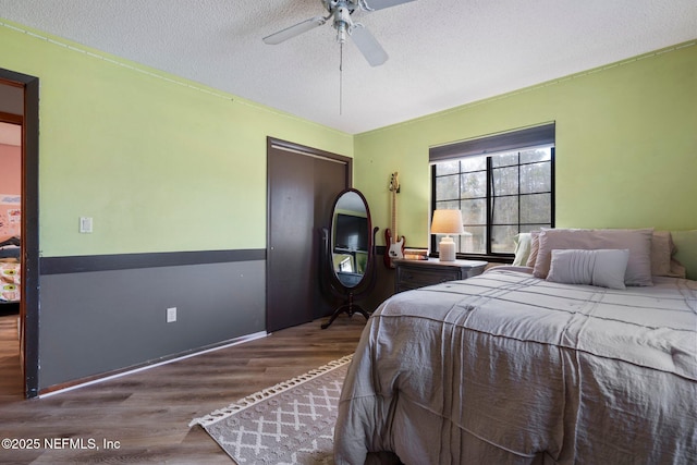 bedroom featuring dark wood-type flooring, ceiling fan, and a textured ceiling