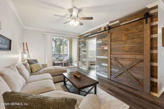 living room with ornamental molding, a barn door, dark hardwood / wood-style floors, and ceiling fan