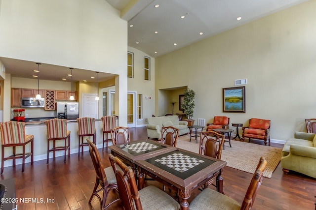 dining room featuring a towering ceiling and dark hardwood / wood-style floors