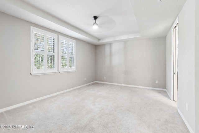 carpeted spare room with ceiling fan, a raised ceiling, and a textured ceiling