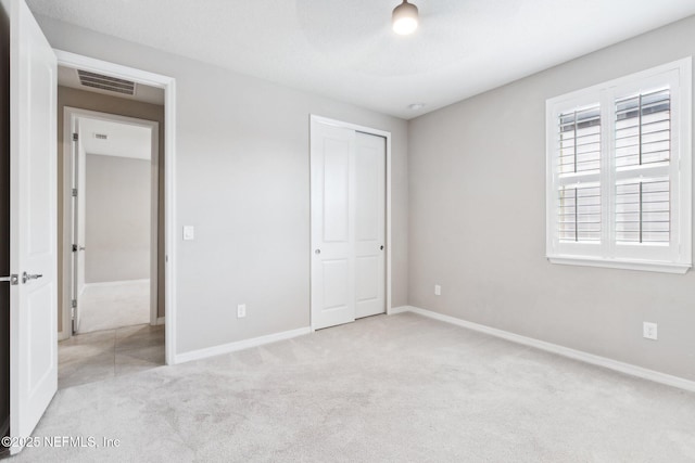 unfurnished bedroom with light carpet and a closet