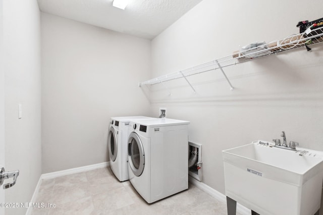 clothes washing area with light tile patterned flooring, independent washer and dryer, and sink