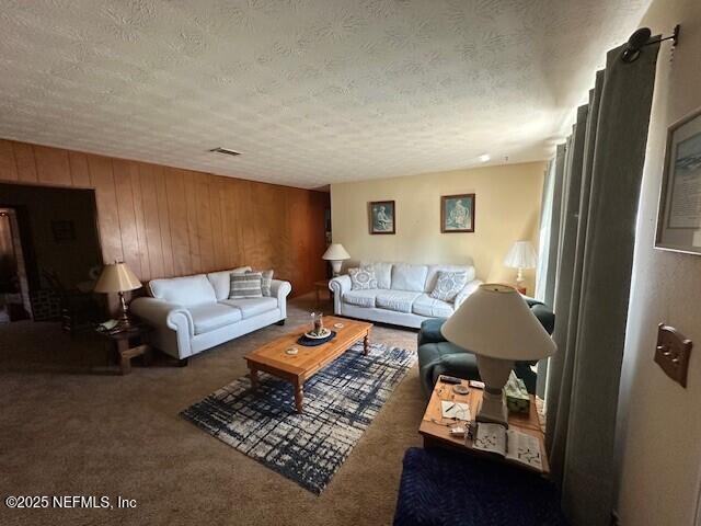 carpeted living room featuring a textured ceiling and wooden walls