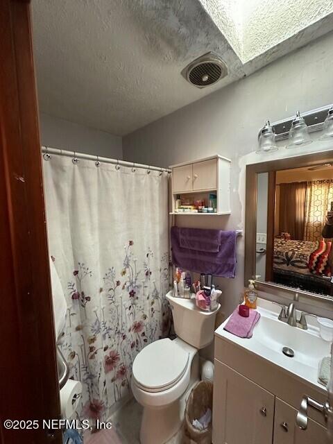 bathroom featuring vanity, a textured ceiling, and toilet