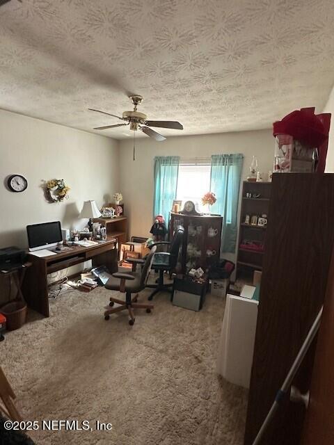 carpeted office space featuring ceiling fan and a textured ceiling