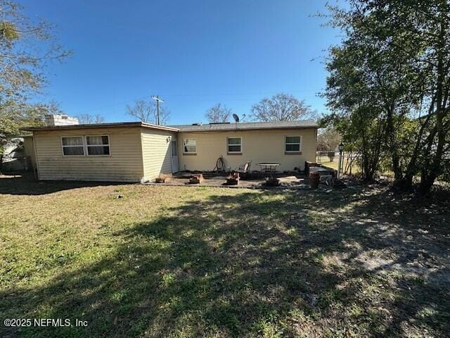 back of property with a lawn and a patio area