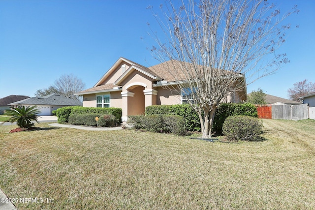 view of front of house with a garage, fence, a front lawn, and stucco siding