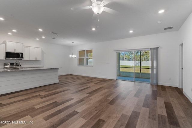 unfurnished living room featuring sink, ceiling fan with notable chandelier, and dark hardwood / wood-style floors