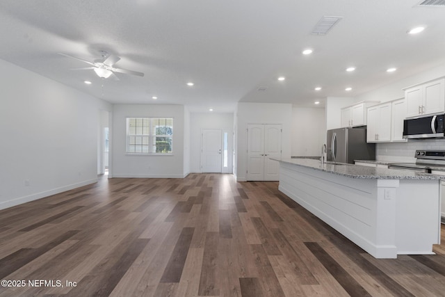 kitchen with appliances with stainless steel finishes, tasteful backsplash, white cabinetry, a large island, and light stone counters