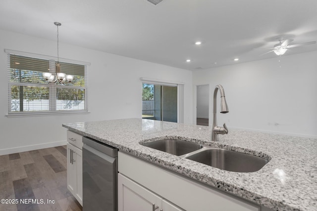 kitchen with pendant lighting, sink, white cabinets, stainless steel dishwasher, and light stone counters