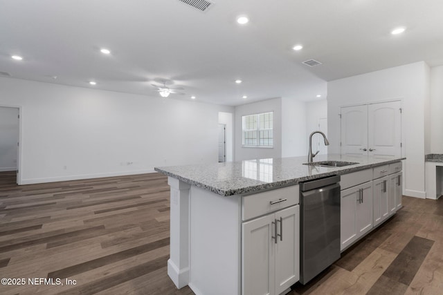 kitchen with dishwasher, sink, white cabinets, light stone countertops, and a center island with sink