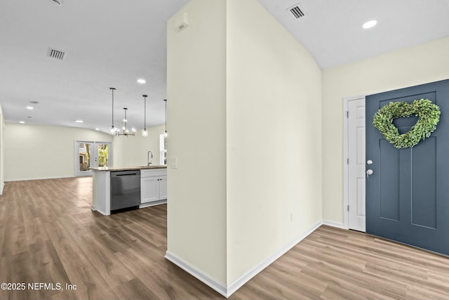 foyer entrance with an inviting chandelier, sink, hardwood / wood-style flooring, and vaulted ceiling