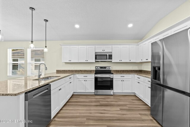 kitchen featuring stainless steel appliances, white cabinetry, hanging light fixtures, and sink