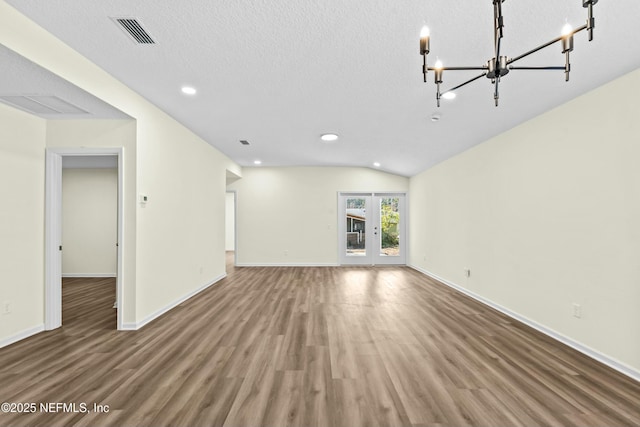 unfurnished living room featuring french doors, vaulted ceiling, hardwood / wood-style floors, and a textured ceiling
