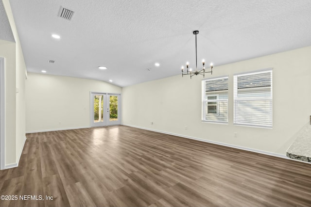 spare room featuring lofted ceiling, dark wood-type flooring, a textured ceiling, and an inviting chandelier