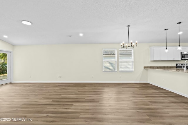 unfurnished living room with an inviting chandelier, hardwood / wood-style floors, and a textured ceiling