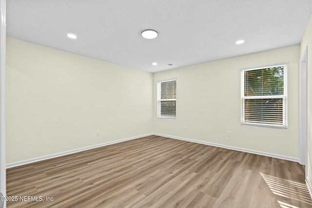 unfurnished room with light hardwood / wood-style floors and a textured ceiling