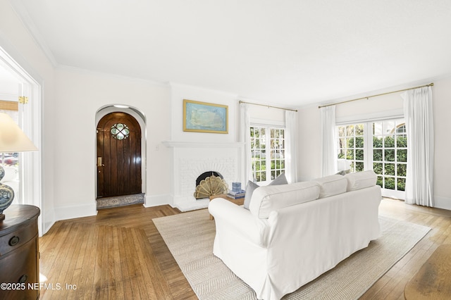 living room featuring crown molding, wood-type flooring, and a brick fireplace