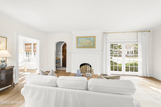 living room with ornamental molding, light hardwood / wood-style floors, and a brick fireplace