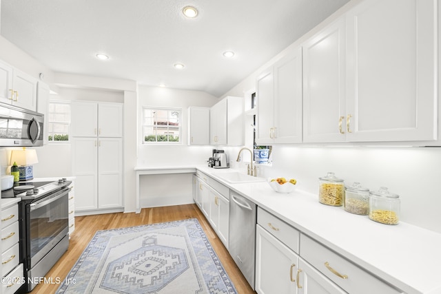 kitchen featuring stainless steel appliances, sink, white cabinets, and light hardwood / wood-style flooring