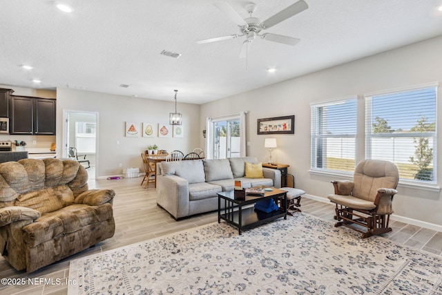 living area with a textured ceiling, light wood-style flooring, and a healthy amount of sunlight