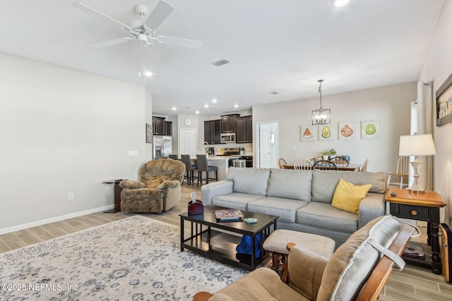 living room with recessed lighting, ceiling fan with notable chandelier, visible vents, baseboards, and wood tiled floor