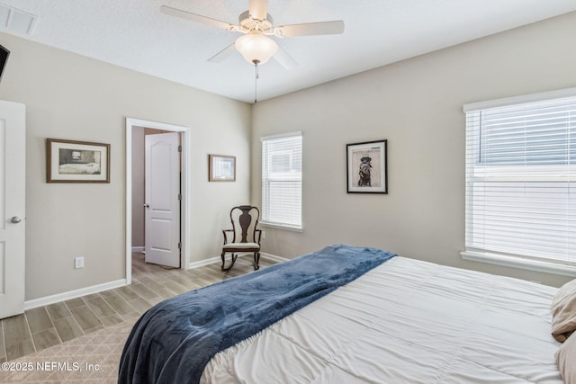 bedroom with light wood finished floors, baseboards, visible vents, and ceiling fan