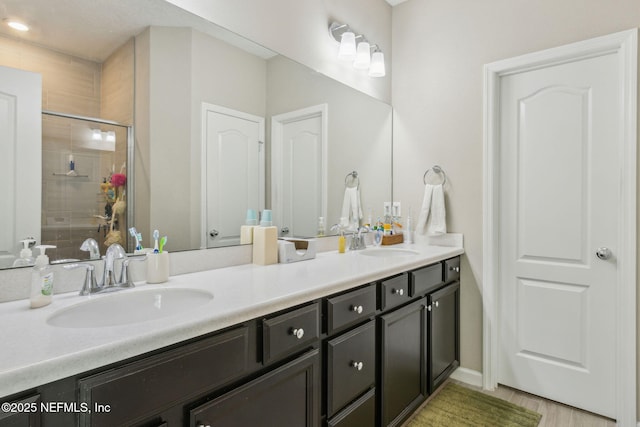 full bath with double vanity, a stall shower, and a sink