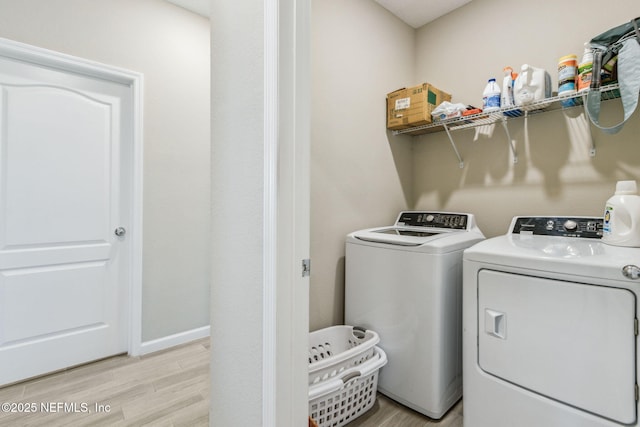 clothes washing area with laundry area, baseboards, light wood finished floors, and washer and dryer