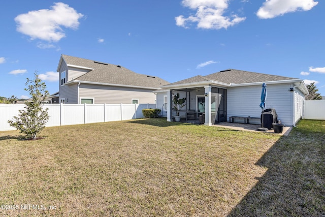 back of property featuring roof with shingles, a lawn, a fenced backyard, and a sunroom