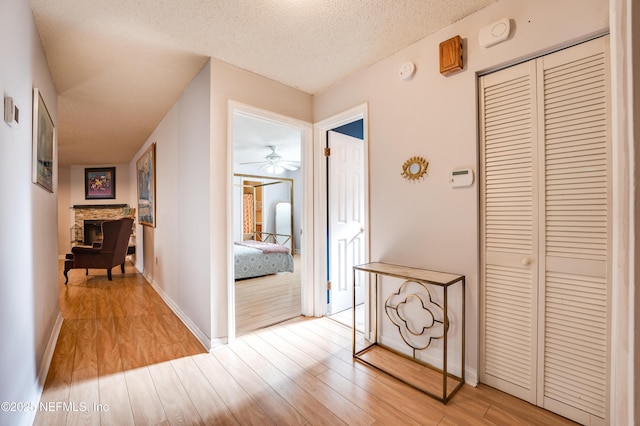 hall featuring light hardwood / wood-style floors and a textured ceiling