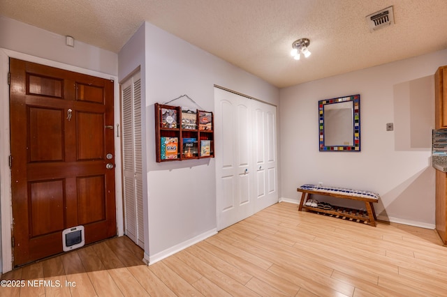 foyer featuring a textured ceiling and light hardwood / wood-style floors