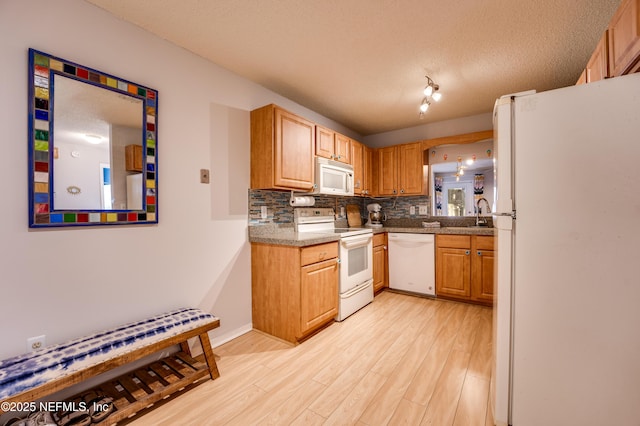 kitchen with tasteful backsplash, white appliances, a textured ceiling, and light wood-type flooring