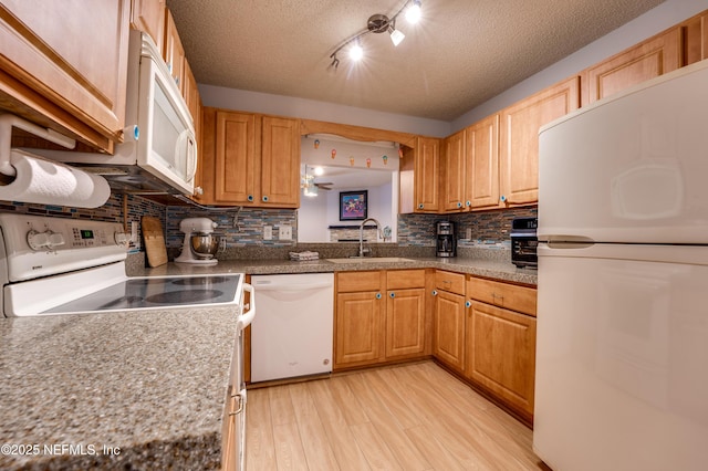 kitchen featuring sink, decorative backsplash, white appliances, light hardwood / wood-style floors, and a textured ceiling