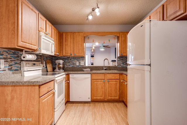 kitchen featuring sink, white appliances, light hardwood / wood-style floors, a textured ceiling, and decorative backsplash