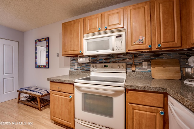 kitchen with backsplash, white appliances, light hardwood / wood-style flooring, and a textured ceiling