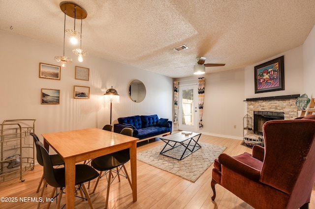 living room with ceiling fan, a textured ceiling, and light wood-type flooring