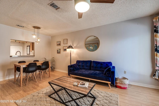 living room with a textured ceiling and light wood-type flooring