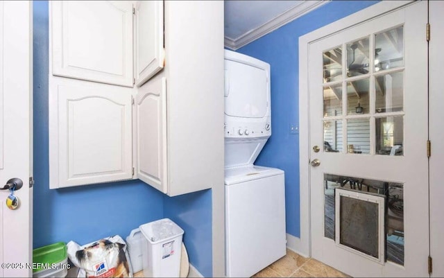 laundry area featuring crown molding, cabinets, and stacked washer / drying machine