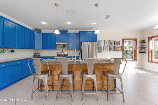 kitchen with stainless steel appliances, a kitchen island, a breakfast bar area, and blue cabinets