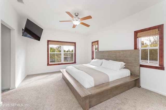 bedroom with ceiling fan, multiple windows, and light carpet