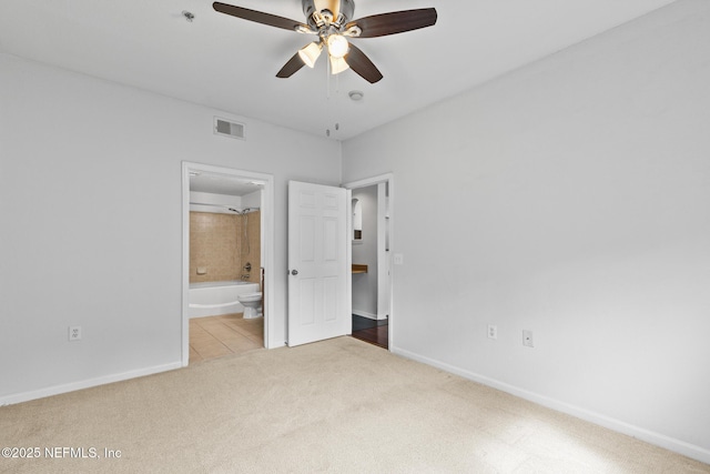 unfurnished bedroom with ensuite bathroom, light colored carpet, and ceiling fan