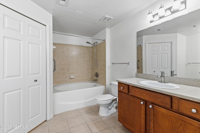 full bathroom featuring tile patterned flooring, vanity, tiled shower / bath combo, toilet, and a textured ceiling