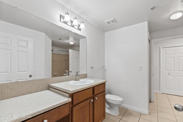 bathroom featuring tile patterned flooring, vanity, a textured ceiling, and toilet