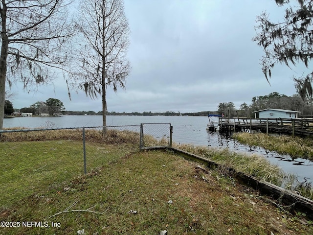 view of dock with a yard and a water view