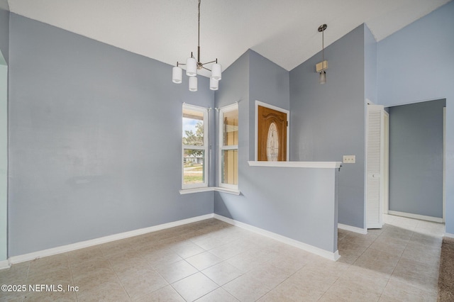 tiled spare room featuring high vaulted ceiling and a chandelier