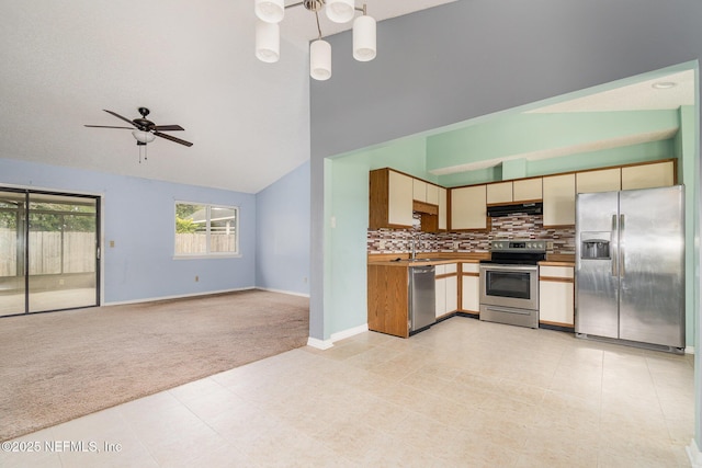 kitchen featuring vaulted ceiling, tasteful backsplash, hanging light fixtures, light colored carpet, and stainless steel appliances