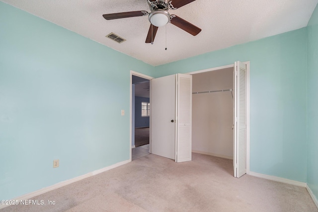 unfurnished bedroom with ceiling fan, light colored carpet, a closet, and a textured ceiling